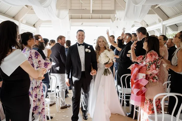 Bride and groom walking down the aisle to cheers and applause, showcasing seamless execution by an On the Day Wedding Coordinator Australia.