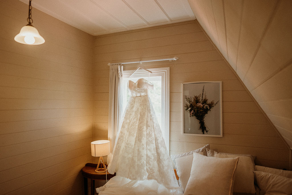 Elegant wedding dress hanging in a serene bedroom setting, ready for a magical day coordinated by an On the Day Wedding Coordinator Adelaide.