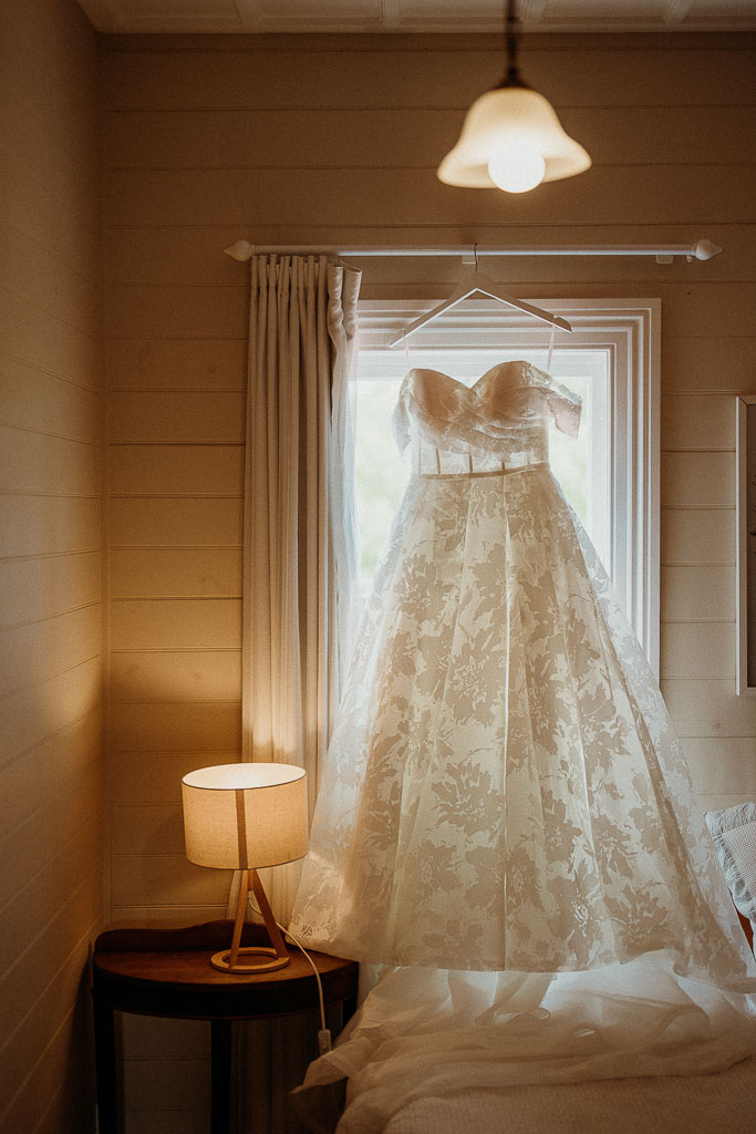 Elegant wedding dress hanging gracefully in a serene room, ready for a perfectly planned day by an On the Day Wedding Coordinator Australia.