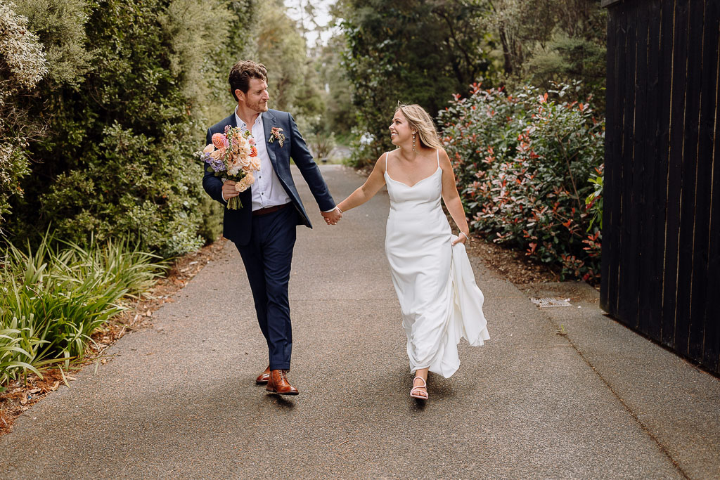 Bride and groom walking hand in hand along a picturesque pathway, exuding joy on their special day, expertly managed by an On the Day Wedding Coordinator Brisbane.