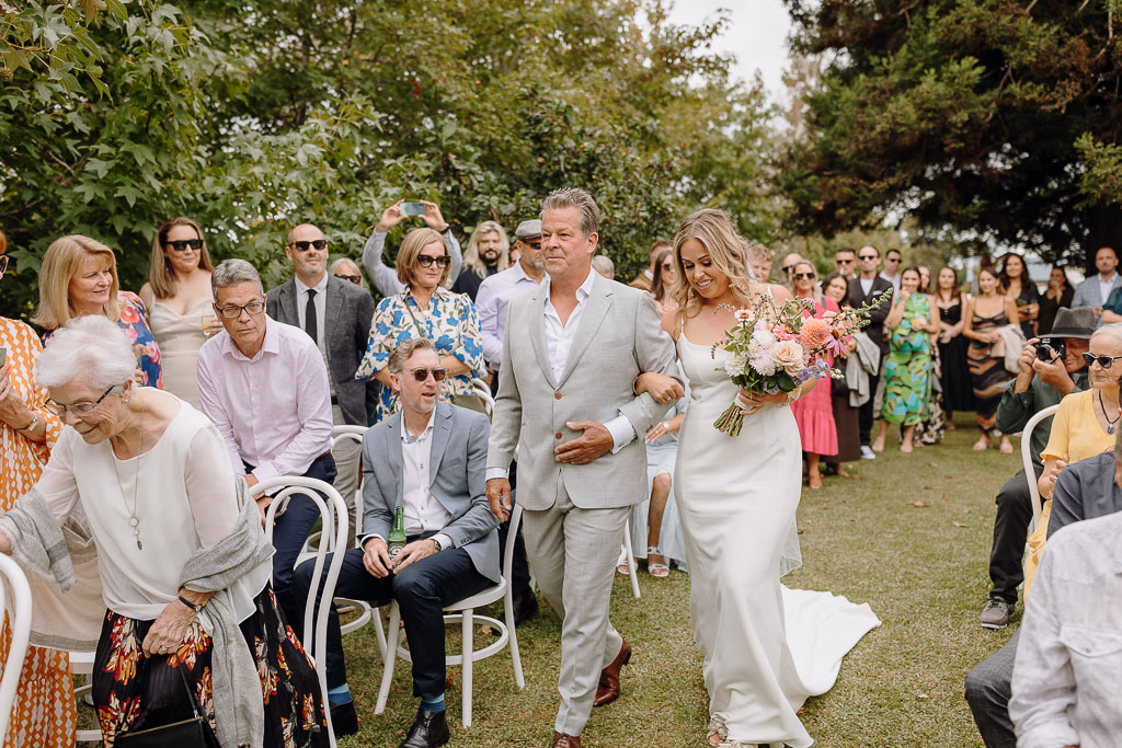 Bride walking down the aisle with her father, surrounded by guests, a beautifully organized moment by an On the Day Wedding Coordinator Brisbane.