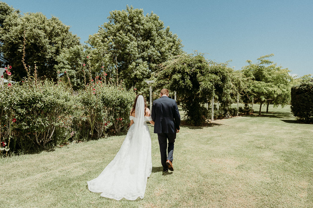 Bride and groom walking hand in hand through a picturesque garden, showcasing the seamless planning by an On the Day Wedding Coordinator Perth.