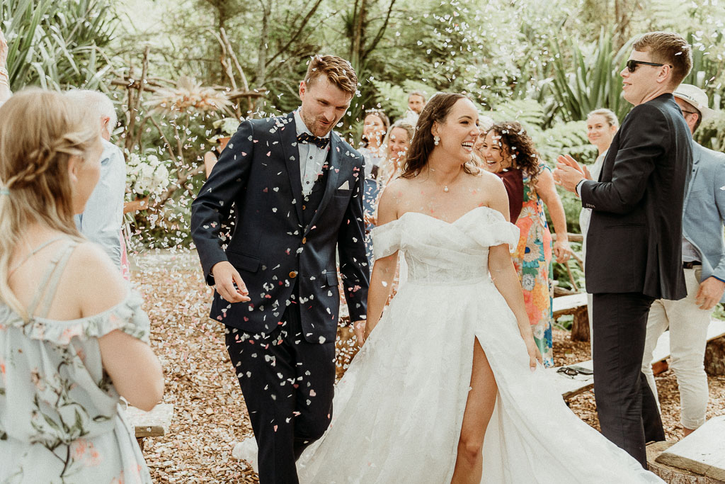 Bride and groom walking down the aisle amidst guests throwing confetti, showcasing a flawless celebration managed by an On the Day Wedding Coordinator Sydney.