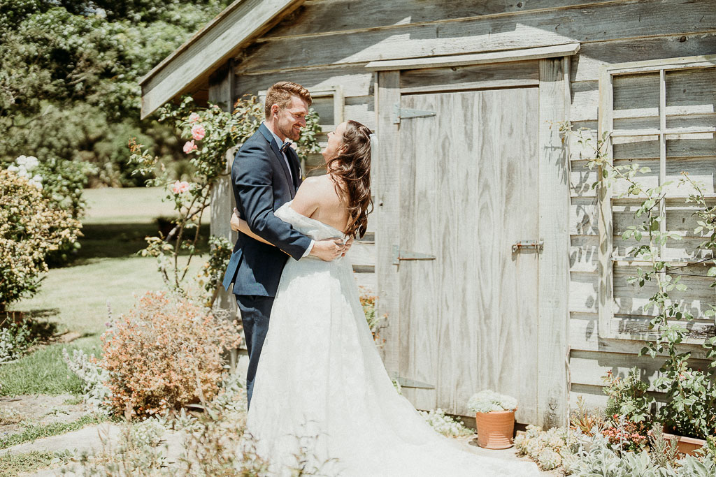 Bride and groom sharing a romantic moment outside a rustic wooden shed, beautifully coordinated by an On the Day Wedding Coordinator Sydney.