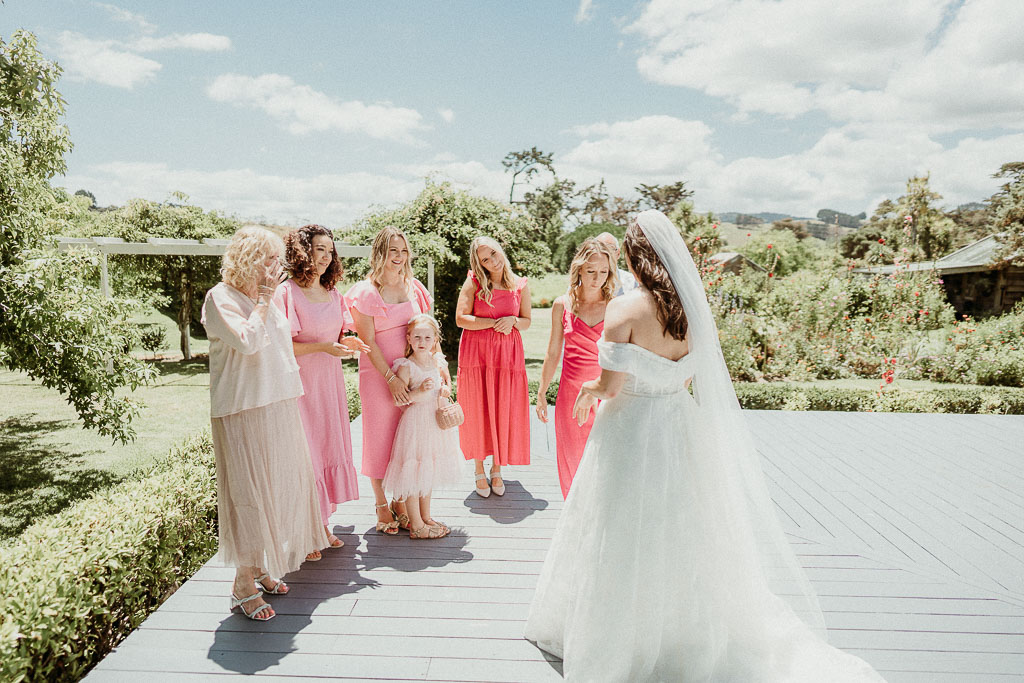 Bride in her wedding gown with her bridesmaids in vibrant pink dresses, enjoying a lighthearted moment, perfectly planned by an On the Day Wedding Coordinator Sydney.